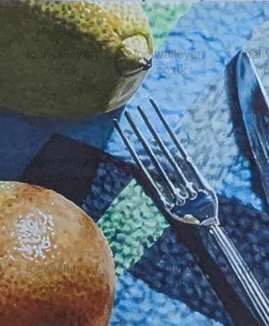 Citrus Lunch Time A close-up of a lemon and an orange next to a fork and knife on a patterned tablecloth.